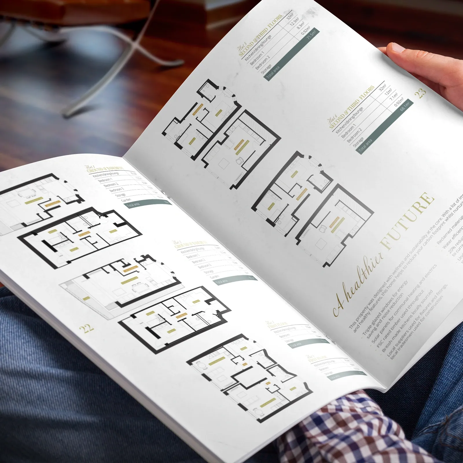 Reader holding the 8 Alderbrook brochure open at the floor plans and A Healthier Future eco credentials spread